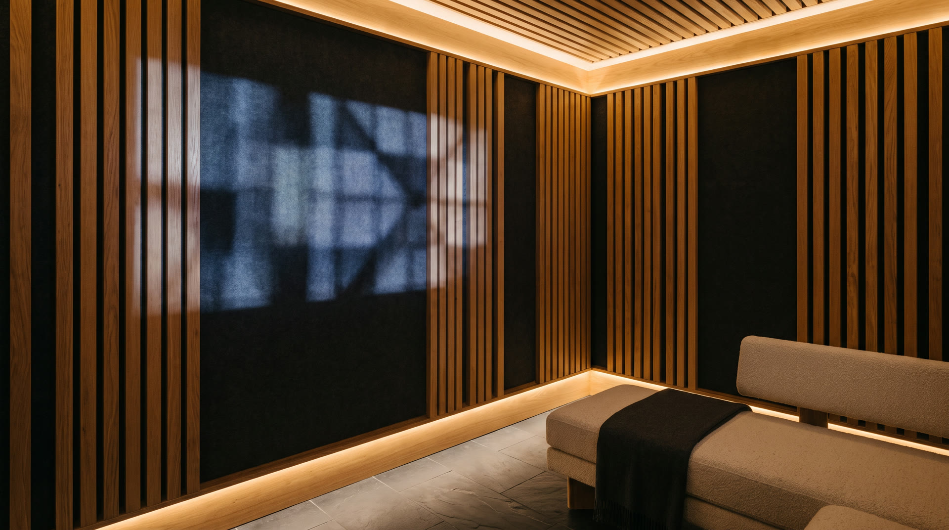 Somatic Space concept: warm oak and acoustic felt with soft indigo light falling across the walls beside a low upholstered seat.
