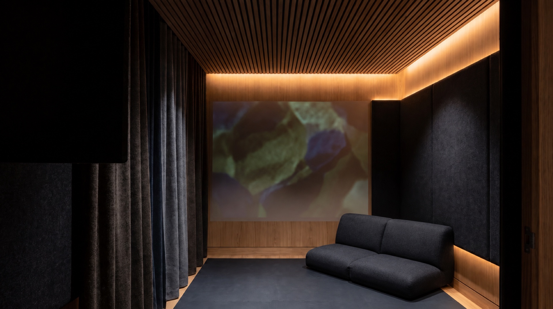 Concept of a private Somatic Space, with a low seat, tactile walls and softly illuminated architectural surfaces.